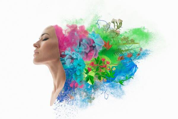 Profile of a woman with closed eyes, from whose head vibrant explosions of colorful paint and floral elements in shades of pink, blue, and green emerge against a white background, symbolizing emotional intelligence.