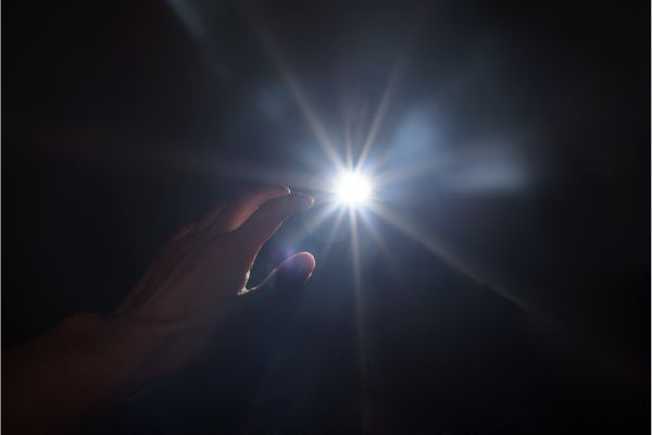 Symbol of hope: Hand seeking light to navigate and overcome negative emotions.